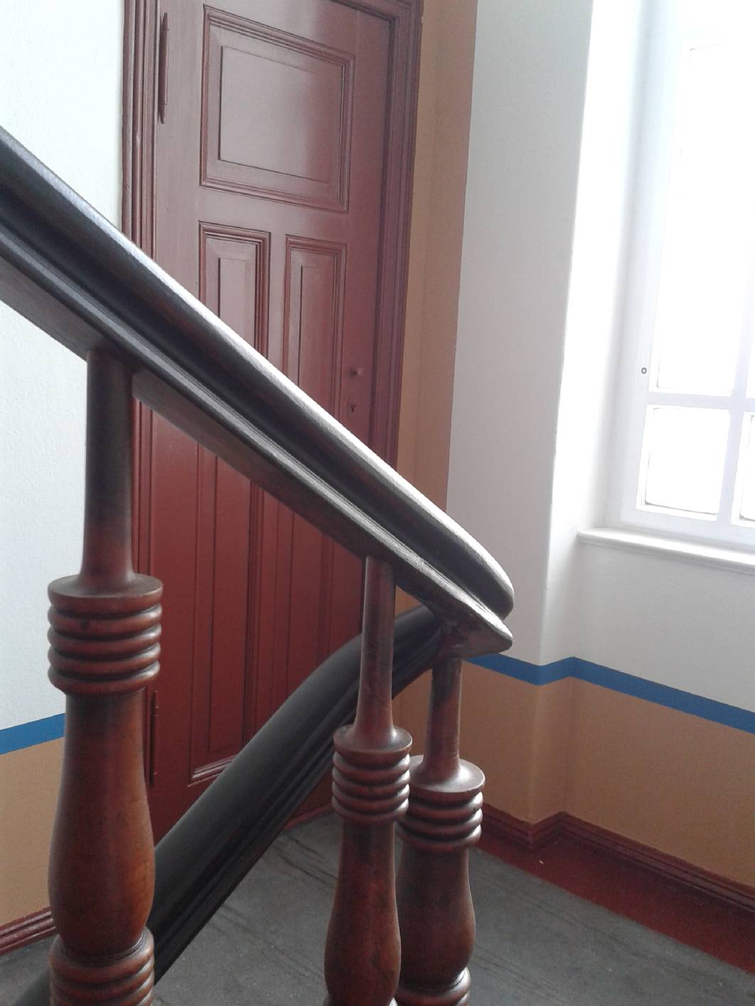 Die mit Schellack - Lasur überarbeiteten Traljen sind stimmig mit den in Ochsenblut gehaltenen Holzbauteilen. Der Sockel in dem aus dem Jugendstil stammenden Treppenhaus aus Berlin wurde gewählt um dem Treppenhaus mehr höhe zu geben. Darüber sitzen Oberwandkassetten. Das Linoleum stammt noch aus der Bebauungszeit. Das Konzept als auch die Malerarbeiten stammen von Malermeister / staatl. gepr. Techniker Norbert Schimpf.